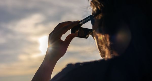 Ein Mann schuat mit einer speziellen Brille für Sonnenfinsternis ins Gegenlicht.