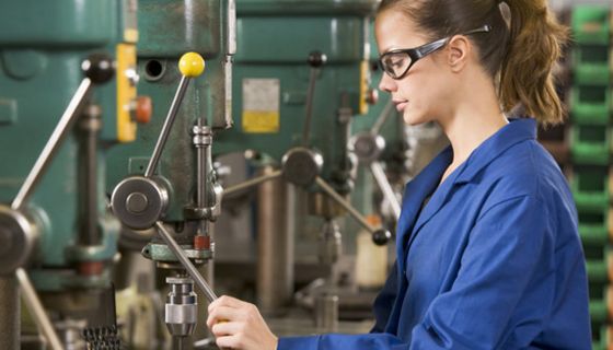 Frau arbeitet an einer Industrie-Maschine