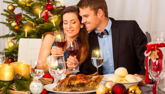 Junges Paar sitzt am Tisch mit Wein und Gänsebraten.