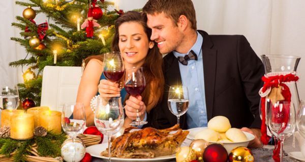 Junges Paar sitzt am Tisch mit Wein und Gänsebraten.