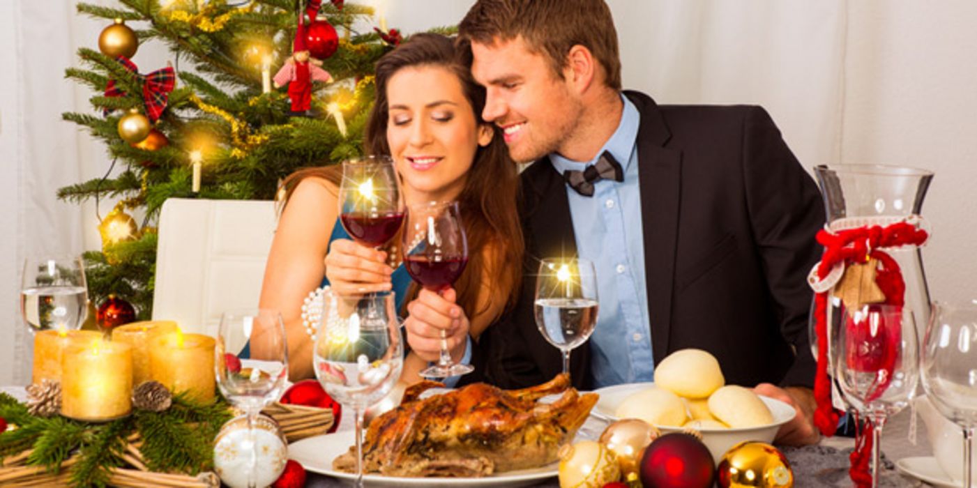 Junges Paar sitzt am Tisch mit Wein und Gänsebraten.