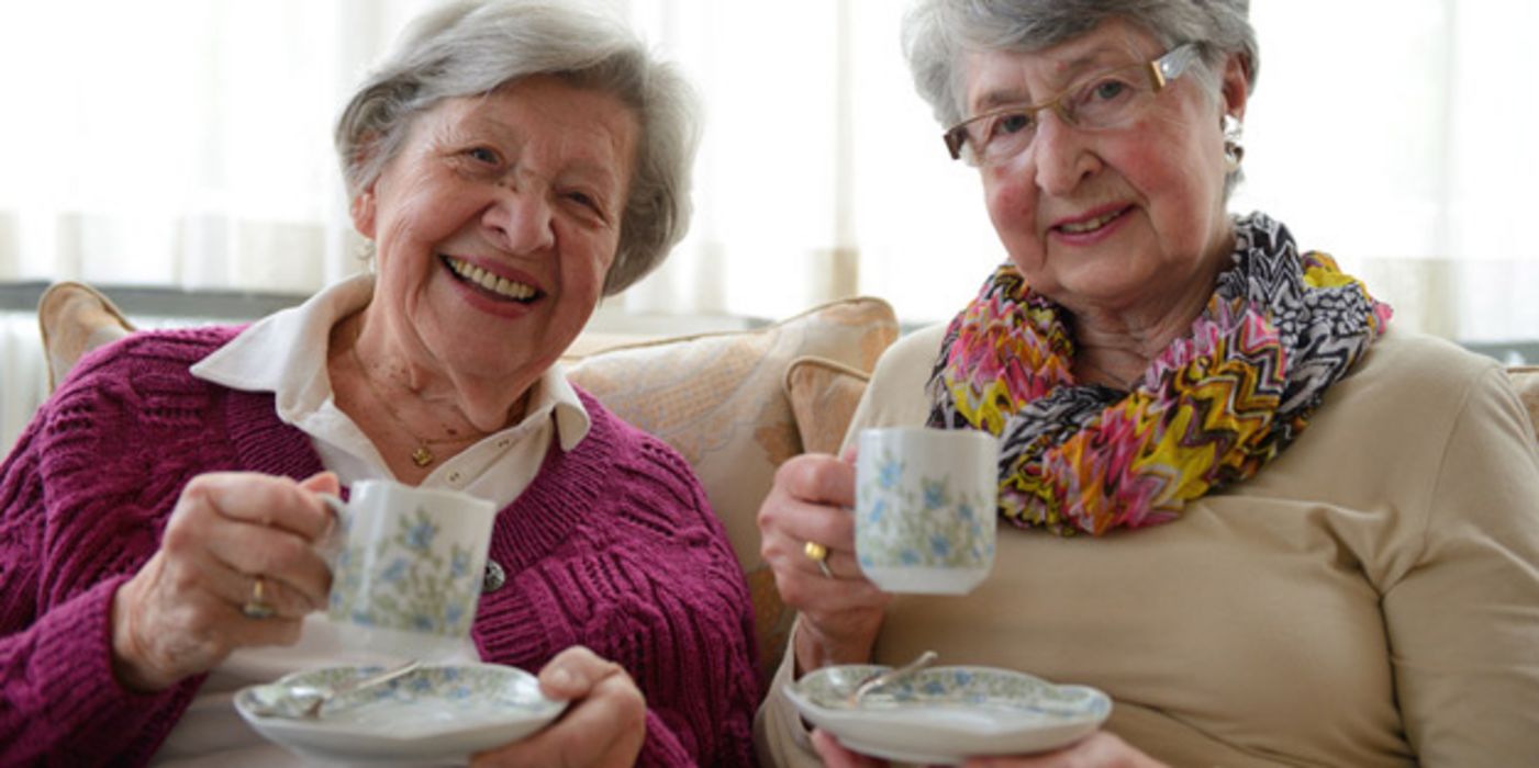 Seniorinnen schick und fröhlich in die Kamera lachend mit jeweils einem "Humpen" mit Untertasse (ca. Mitte 70)