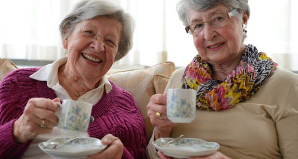 Seniorinnen schick und fröhlich in die Kamera lachend mit jeweils einem "Humpen" mit Untertasse (ca. Mitte 70)