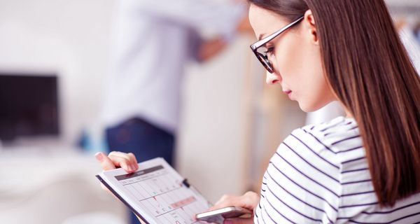 Frau blickt auf einen Monatskalender, in dem einzelne Tage rot markiert sind – darunter auch eine Strecke von vier Tagen hintereinander.