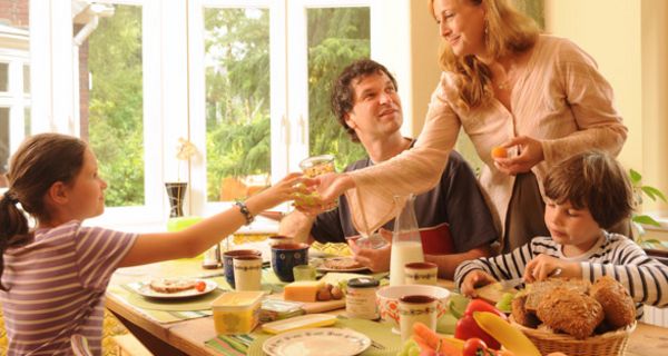 Familie: Vater, Mutter in den 30ern, Mädchen, ca. 10 Jahre, Junge ca. 7 Jahre, beim üppigen Frühstück