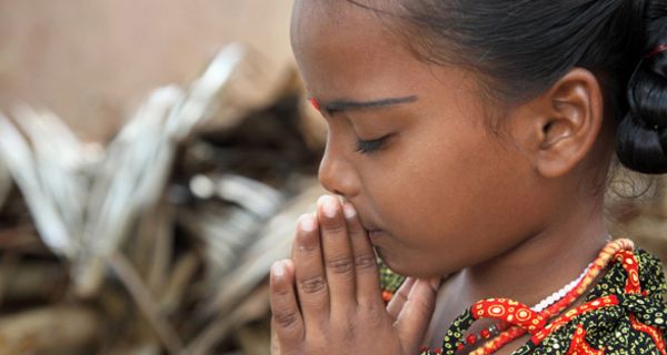 Indisches Mädchen hat die Hände zum Gebet zusammengelegt und die Augen geschlossen