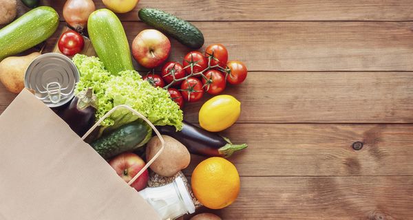 Tüte, aus der Obst und Gemüse herausschaut.