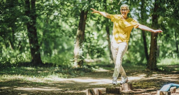 Frau balanciert auf Baumstümpfen im Wald.