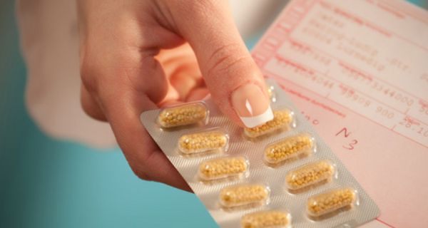 Frau hält Kaspel-Blister und Kassenrezept in der Hand