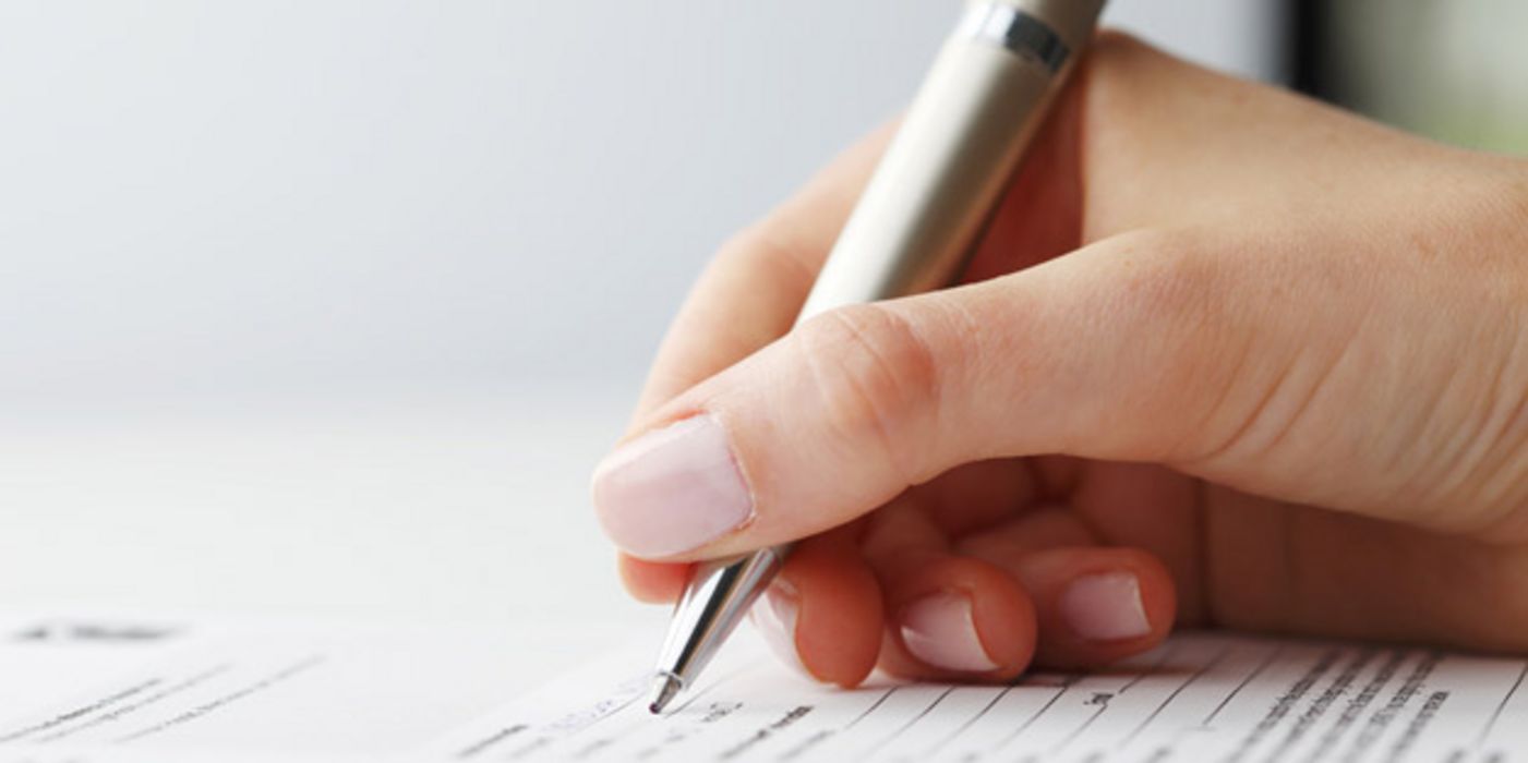 Frauenhand mit Kugelschreiber beim Ausfüllen eines Formulars