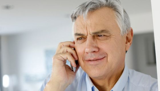 Portrait grauhaariger Mann ca. Mitte 60 mit Handy am Ohr