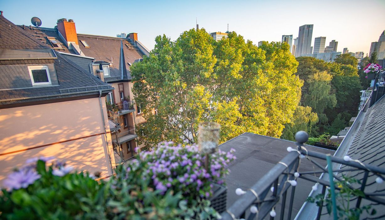 Foto von einem Balkon mit Blick in die Stadt und auf einen Baum.