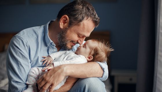 Vater, hält Baby im Arm.