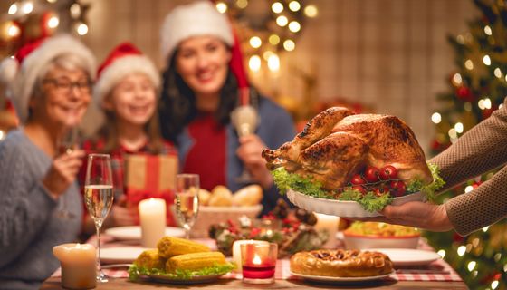 Familie sitzt beim Weihnachtsessen und freut sich auf die Gans.