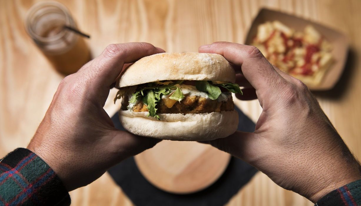 Foto von Händen, die einen Burger halten.