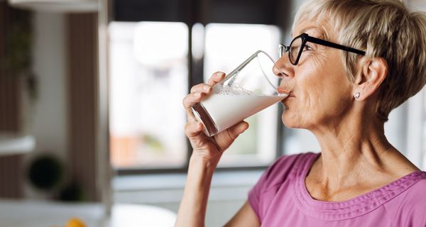 Ältere Frau, trinkt ein Glas Milch.