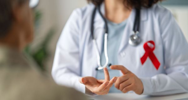 Ärztin mit AIDS-Schleife berät Patienten.