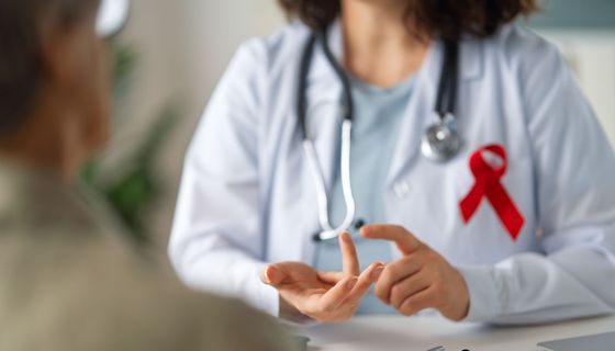 Ärztin mit AIDS-Schleife berät Patienten.