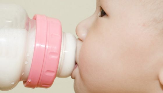 Baby trinkt aus einem Fläschchen Milch