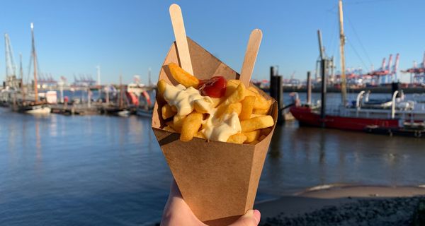 Portion Pommes mit Ketchup und Mayonnaise in einer Papptüte.