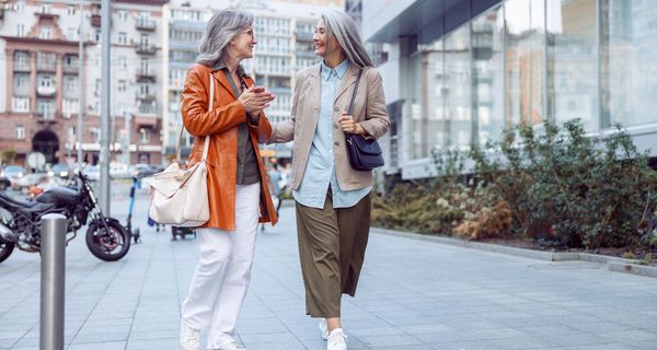 Zwei ältere Frauen schlendern durch eine Stadt.