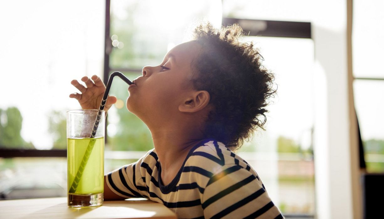 Kleiner Junge, trinkt einen Softdrink mit Strohhalm.