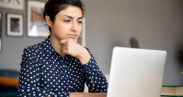 Junge Frau, sitzt vor ihrem Laptop.