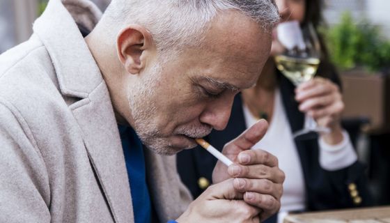 Ein älterer Mann, mindestens 50 Jahre alt, zündet sich eine Zigarette an.