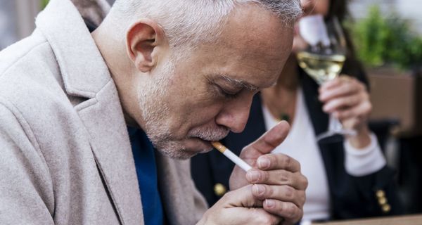 Ein älterer Mann, mindestens 50 Jahre alt, zündet sich eine Zigarette an.