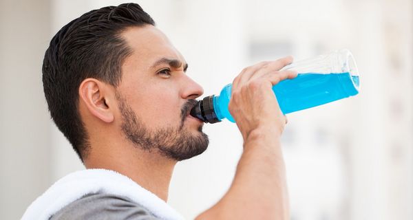 Ein Mann trinkt aus einer Flasche mit einer leuchtend blauen Flüssigkeit.