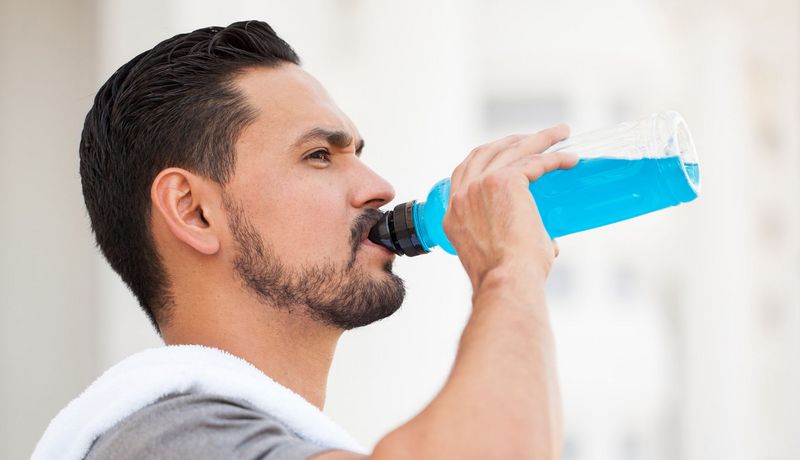 Ein Mann trinkt aus einer Flasche mit einer leuchtend blauen Flüssigkeit.