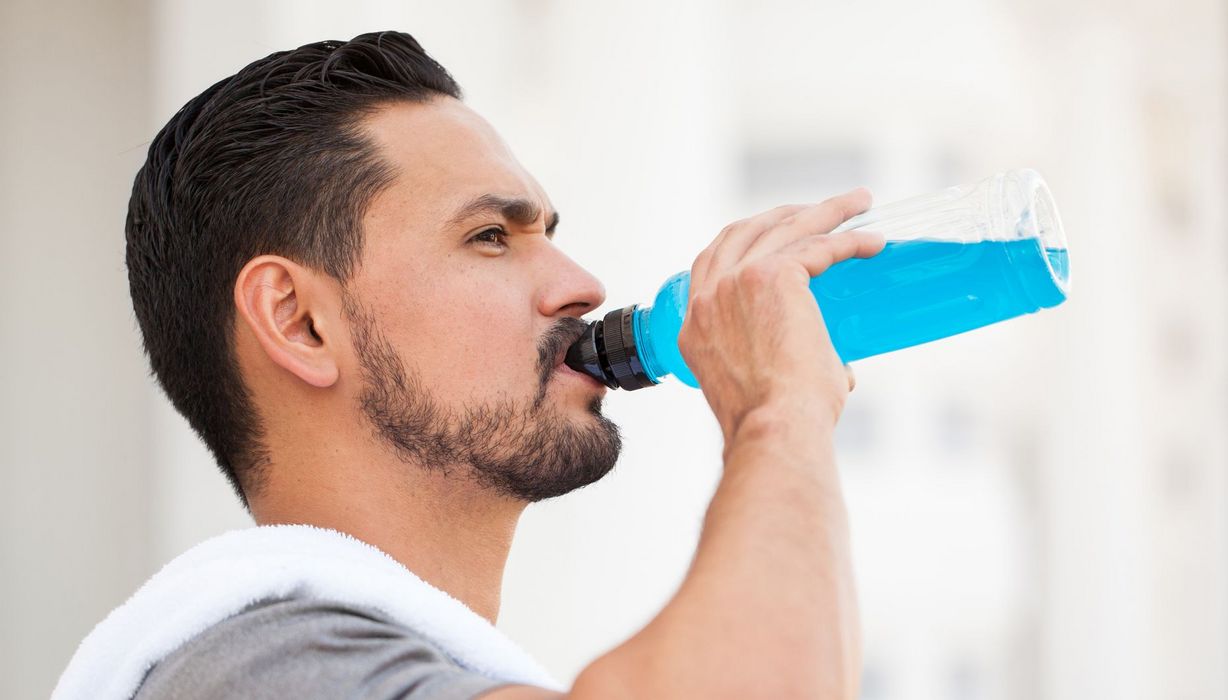 Ein Mann trinkt aus einer Flasche mit einer leuchtend blauen Flüssigkeit.