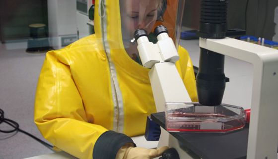 Forscherin in Vollschutzanzug unter Hochsicherheitsbedingungen