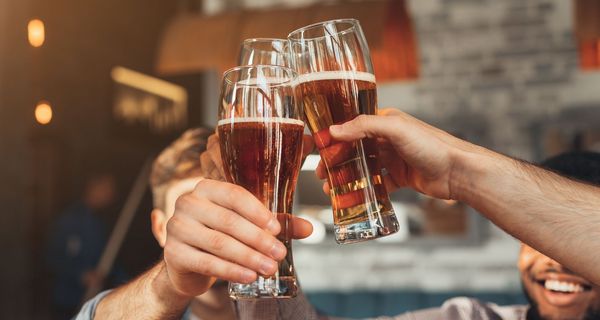 Männer, prosten sich mit einem Bier zu.