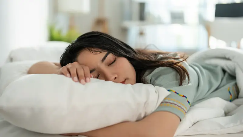 Frau, liegt im Bett und schläft.