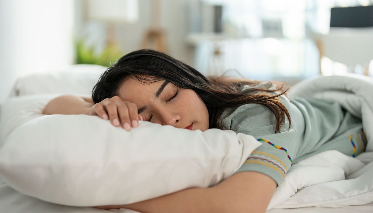 Frau, liegt im Bett und schläft.