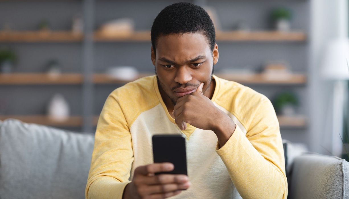 Mann, schaut skeptisch in sein Smartphone.