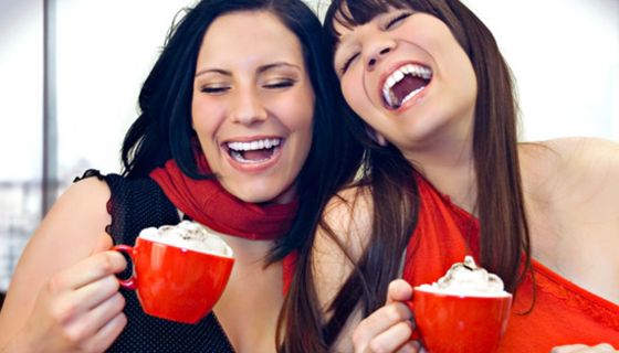 Zwei Frauen trinken Kakao aus roten Tassen.