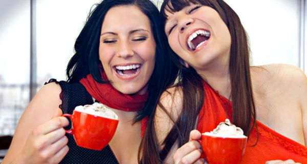 Zwei Frauen trinken Kakao aus roten Tassen.