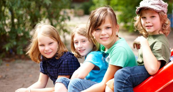 Vier Kinder sitzen auf einer roten Rutsche.