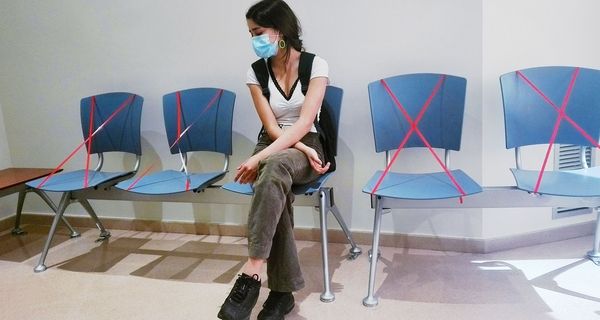 Junge Frau, sitzt beim Arzt im Wartezimmer.