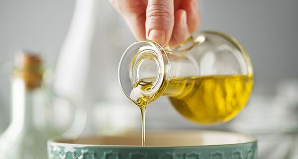 Frau, gießt Olivenöl in ein Gefäß.