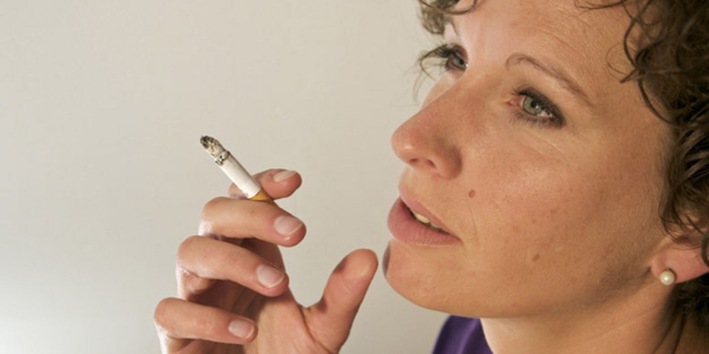 Profilbild einer Frau ca. Ende 30, lockige, braune Haare, schaucht nach oben, in der Hand eine Zigarette