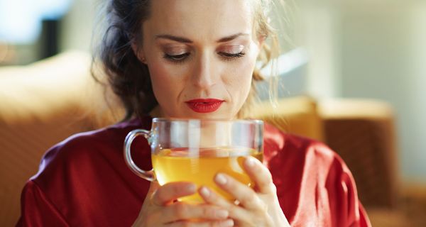 Frau blickt auf eine große Tasse grünen Tees in ihren Händen.