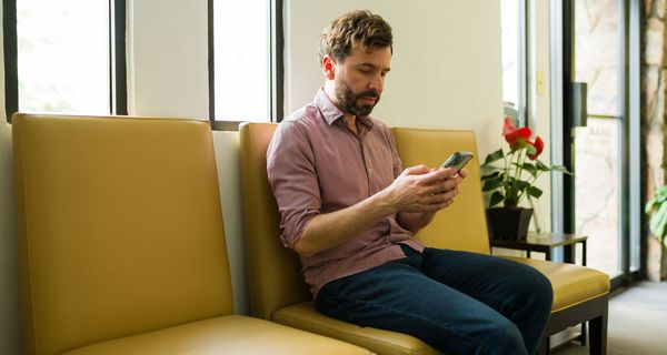 Mann sitz auf Sofa und schaut auf ein Handy