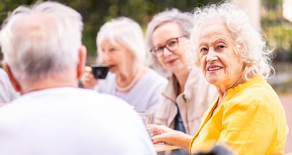 ältere Frau sitzt mit anderen älteren Menschen zusammen