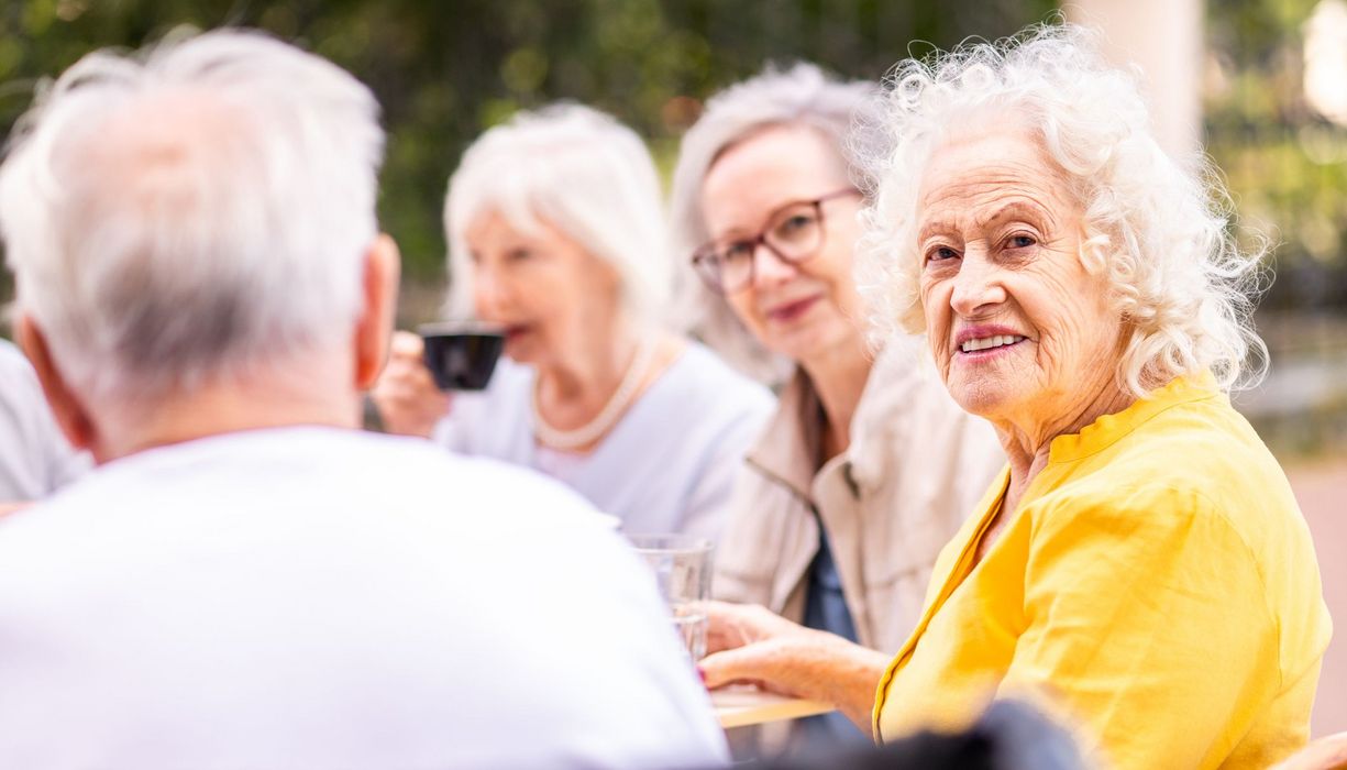 ältere Frau sitzt mit anderen älteren Menschen zusammen
