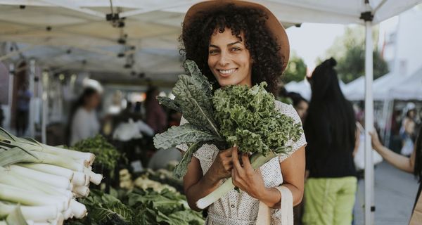 Frau mit Gemüse am Marktstand.