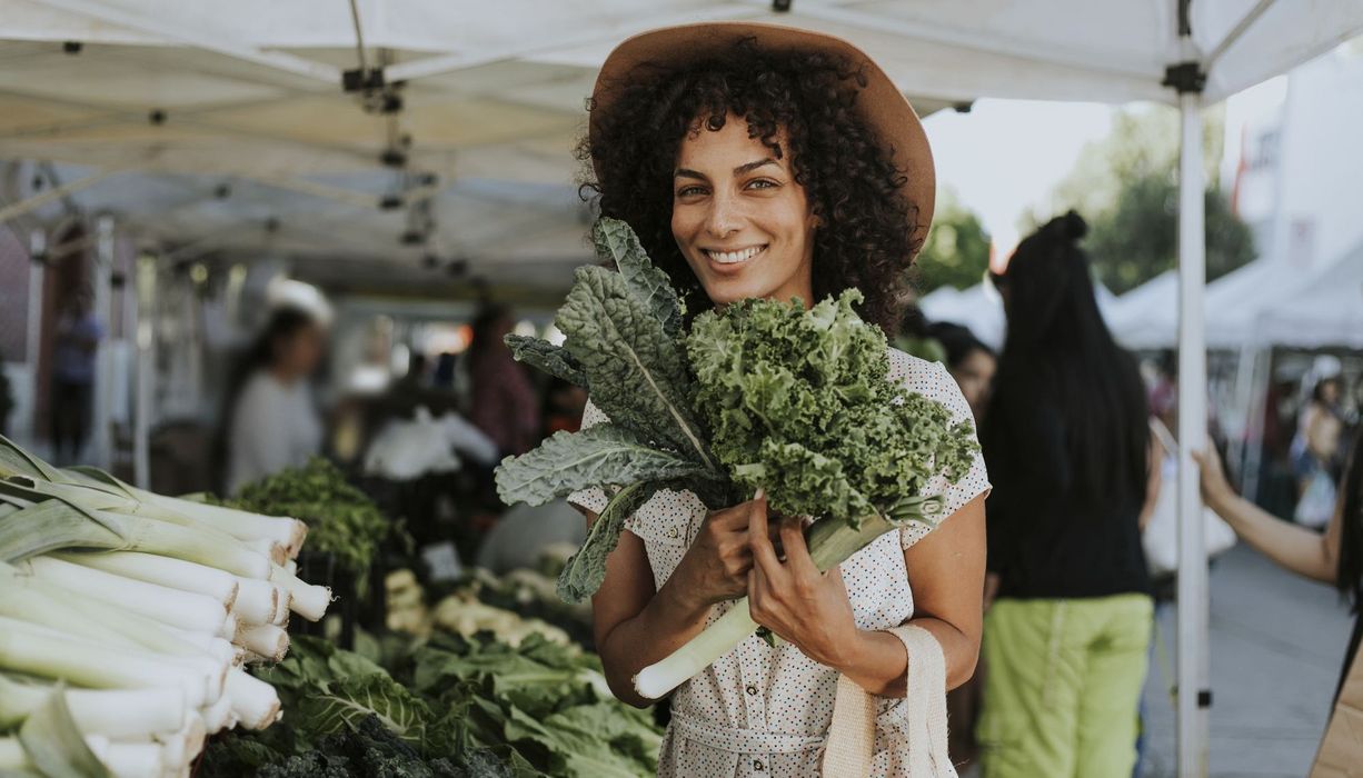 Frau mit Gemüse am Marktstand.
