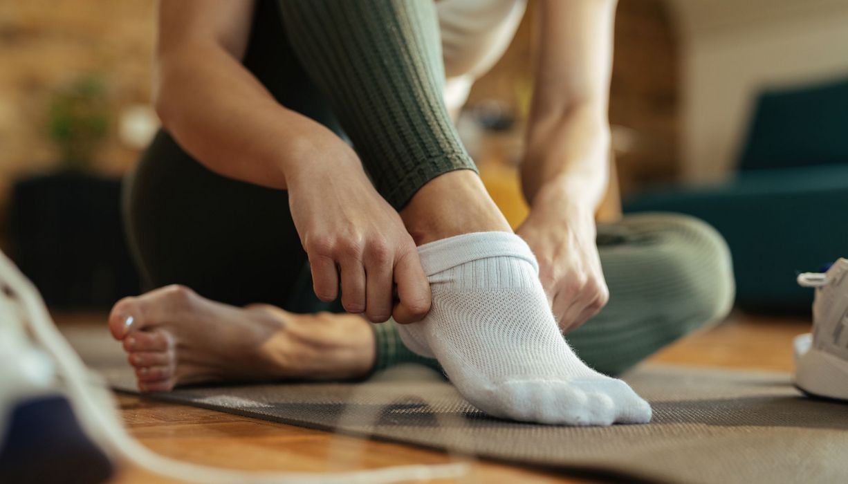 Frau, zieht sich Socken an.